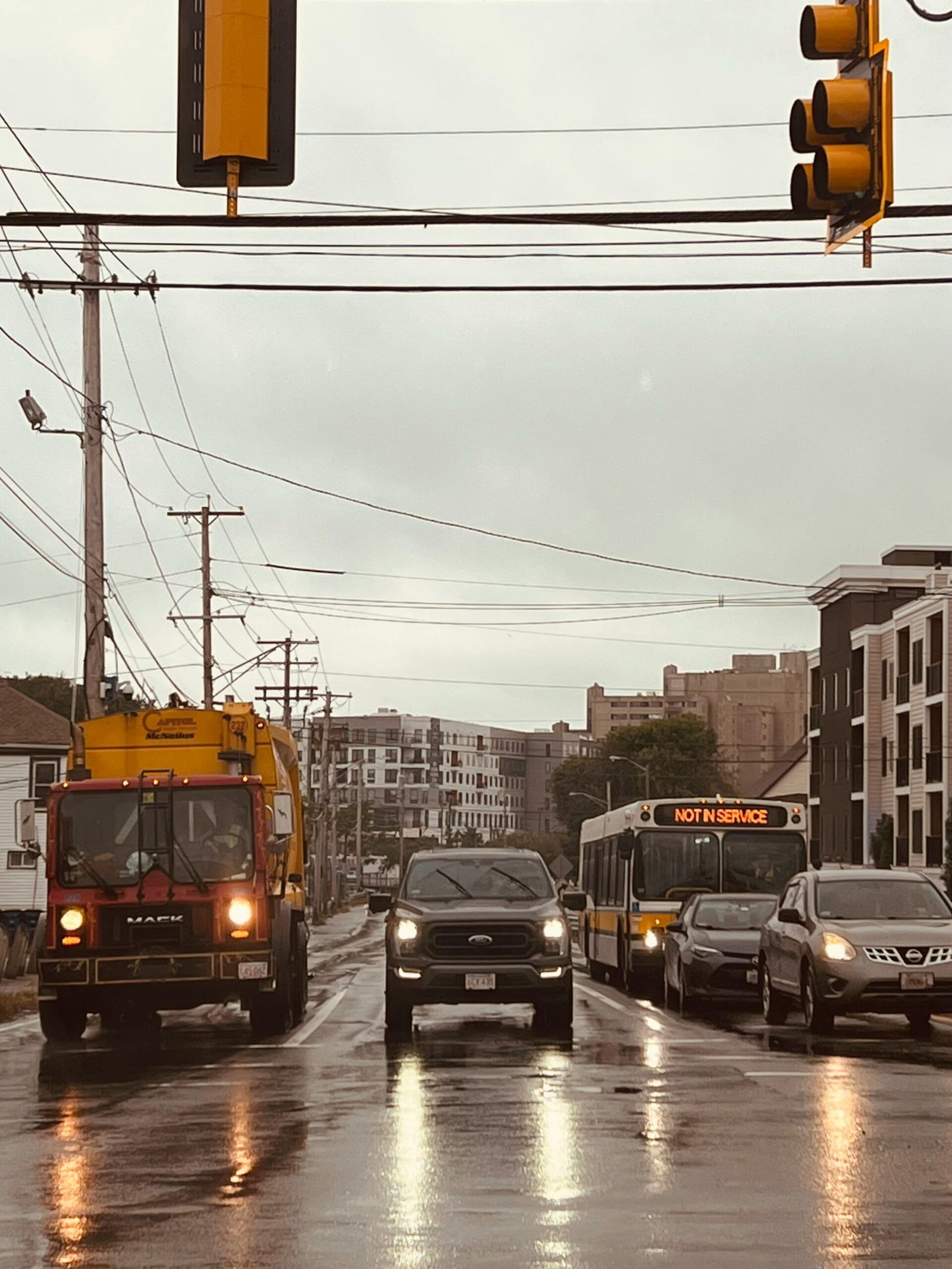 A rainy day in Boston captures vehicles on a wet road, showcasing urban life.